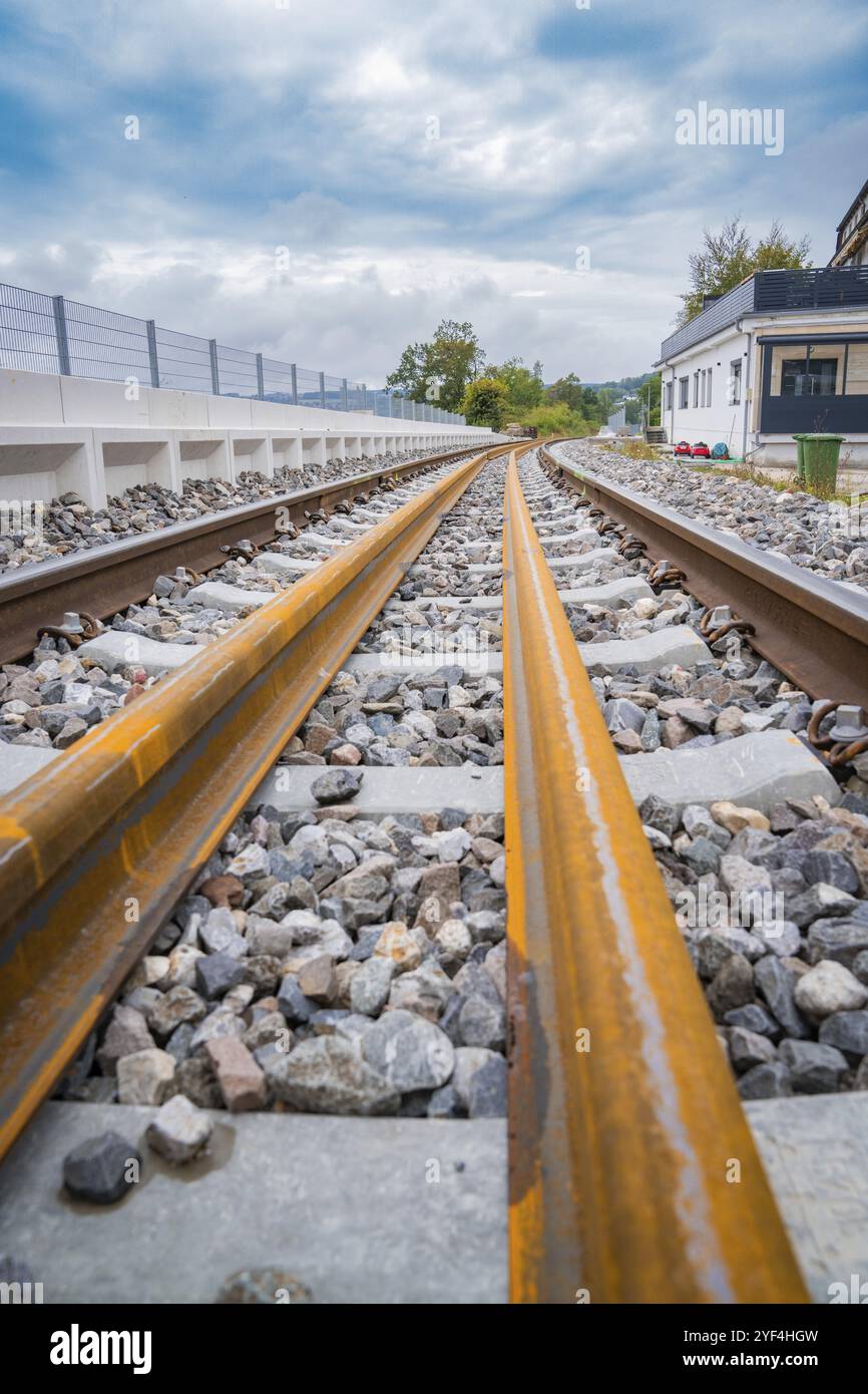 Nahaufnahme von Schienen mit Steinbettung, die unter bewölktem Himmel in die Ferne verlaufen, Gleisbau, Bahnlieferung für Hermann Hessebahn, Calw Stockfoto