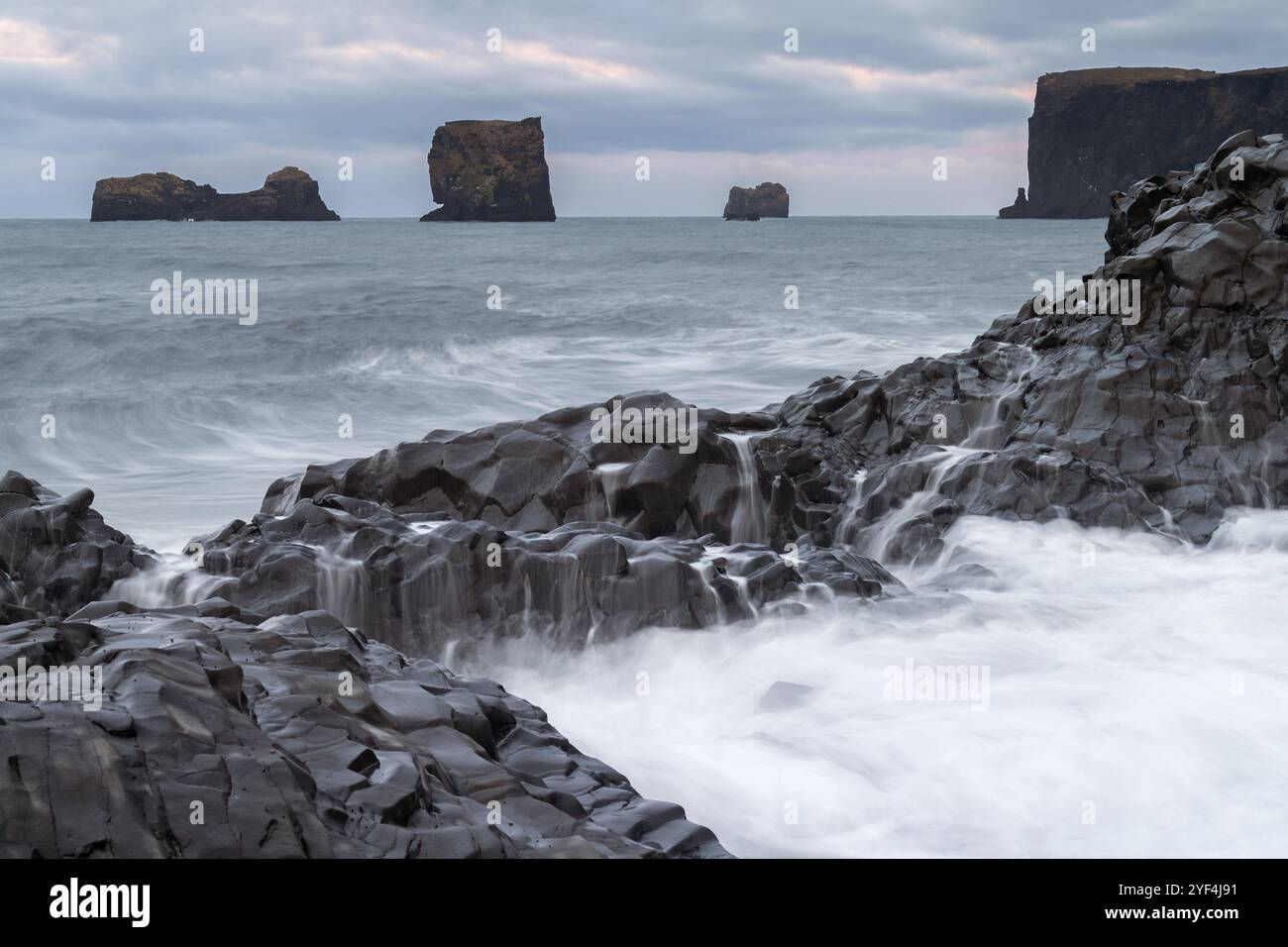 Wellen, Surfen, über Säulenbasalt gespült, Felsnadeln, lange Exposition, Dyrholafjara, Felsentor Dyrholaey oder Dyrholaey, Südküste, Island, Europa Stockfoto