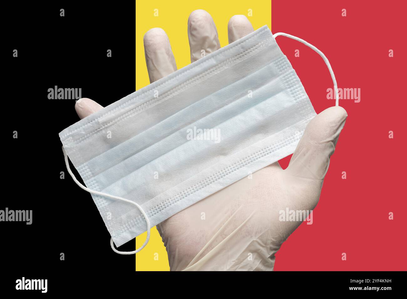 Doktor hält Gesichtsmaske in weißen medizinischen Handschuhen auf der Flagge der Hintergrundfarben Belgiens in der Hand. Konzept Pandemieversicherung Coronavirus, durch die Luft übertragbare Krankheiten Stockfoto
