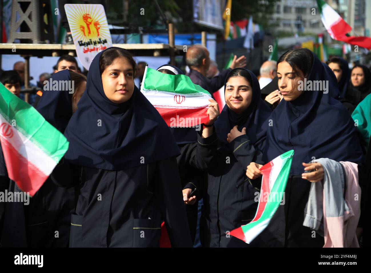 Teheran, Iran. November 2024. Iranische verschleierte Schulmädchen schwenken die iranische Flagge während einer Anti-US-Kundgebung zum 45. Jahrestag der Übernahme durch die US-Botschaft vor dem ehemaligen Botschaftsgebäude in Teheran. Am 4. November 1979 übernahmen iranische Studenten die US-Botschaft in Teheran und hielten über 50 amerikanische Diplomaten und Wärter 444 Tage lang als Geiseln. Diese Aktion folgte der Entscheidung der USA, dem entlassenen Schah aus dem Iran die medizinische Behandlung in Amerika zu erlauben. Vor kurzem, am 2. November, warnte der Oberste Führer Ayatollah Ali Khamenei vor einer ernsten Reaktion auf die USA und Israel nach der jüngsten israelischen Mission Stockfoto