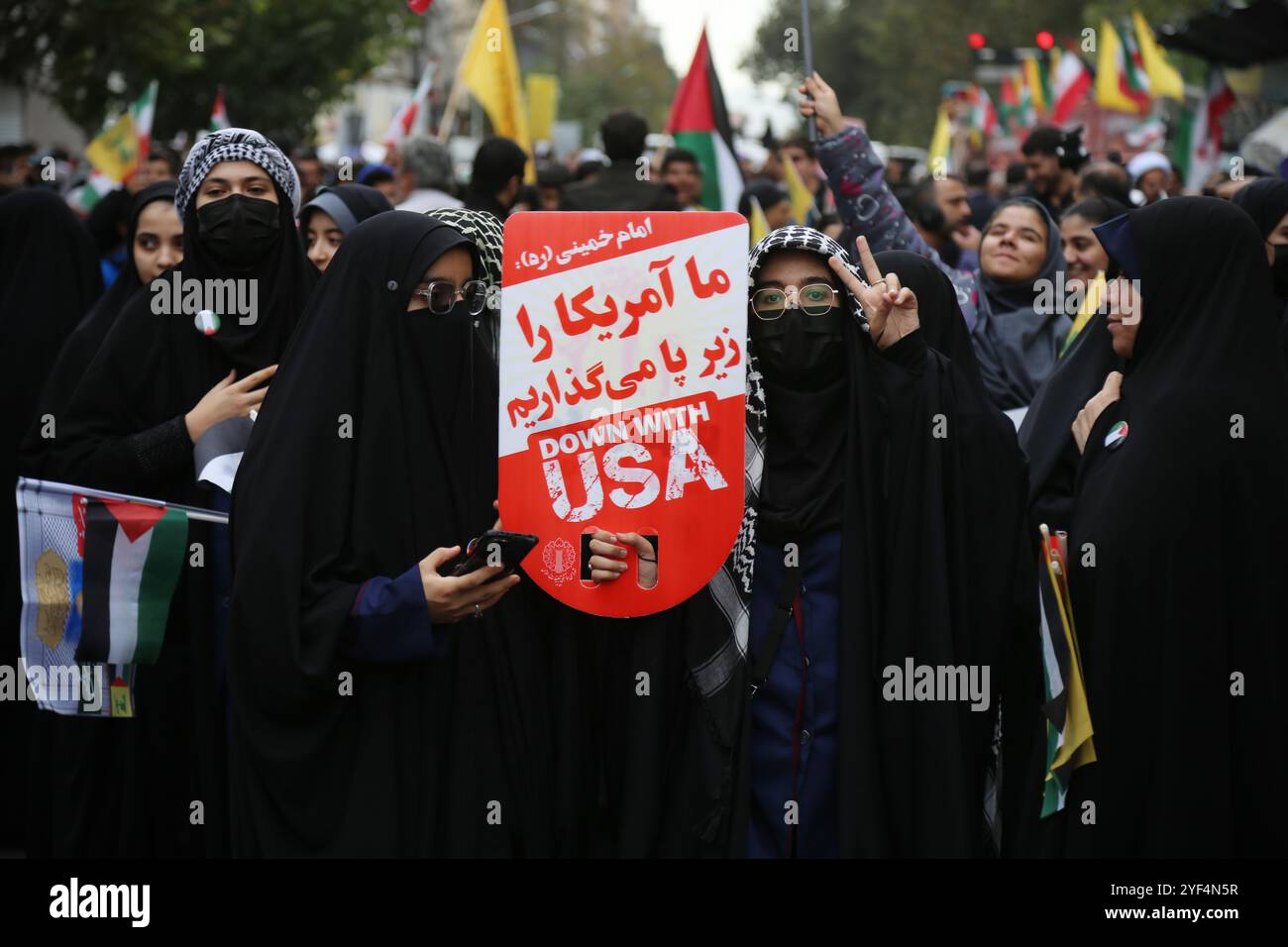Teheran, Iran. November 2024. Eine verhüllte iranische Frau hält ein Poster mit dem Aufschrift „Down with the U.s.a“ während einer Anti-US-Kundgebung zum 45. Jahrestag der Übernahme durch die US-Botschaft vor dem ehemaligen Botschaftsgebäude in Teheran. Am 4. November 1979 übernahmen iranische Studenten die US-Botschaft in Teheran und hielten über 50 amerikanische Diplomaten und Wärter 444 Tage lang als Geiseln. Diese Aktion folgte der Entscheidung der USA, dem entlassenen Schah aus dem Iran die medizinische Behandlung in Amerika zu erlauben. Vor kurzem, am 2. November, warnte der Oberste Führer Ayatollah Ali Khamenei vor einer ernsten Reaktion auf die USA und Israel Stockfoto