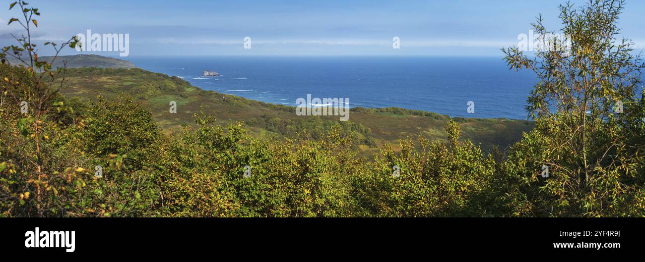 Atemberaubendes Panorama der Pazifikküste: Wellen im blauen Pazifik und Ufer, die an sonnigen Herbsttagen mit Wald bewachsen sind. Halbinsel Kamtschatka, Avach Stockfoto