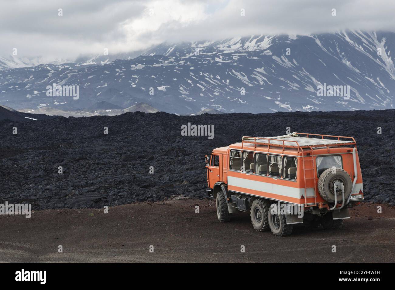 HALBINSEL KAMTSCHATKA, RUSSLAND, 24. JUNI 2016: Russischer Expeditionswagen KamAZ (6-Rad-Fahrt) auf Bergstraße vor dem Hintergrund von Lavafeldern und Vulkanen Stockfoto