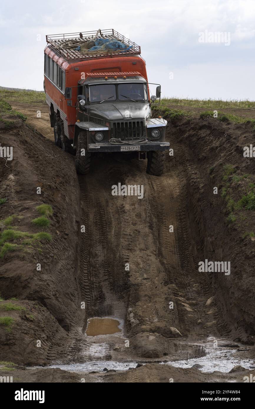 Russischer Offroad-Extremexpeditionswagen Ural fährt auf schmutziger, matschiger Bergstraße, transportiert Touristen in Richtung Reiseziele für Klimabedingungen Stockfoto