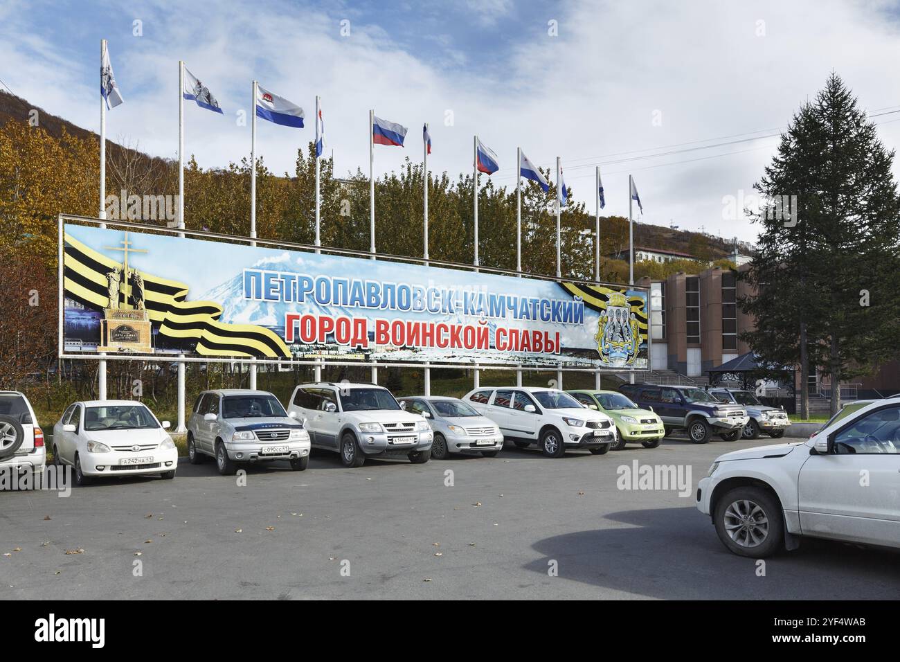 PETROPAVLOVSK-KAMTSCHATSKI STADT, KAMTSCHATKA, RUSSLAND, 12. OKTOBER 2016: Poster Petropavlovsk-Kamtschatski, Stadt des Militärruhmes und Fahnenmasten mit Fliegen Stockfoto