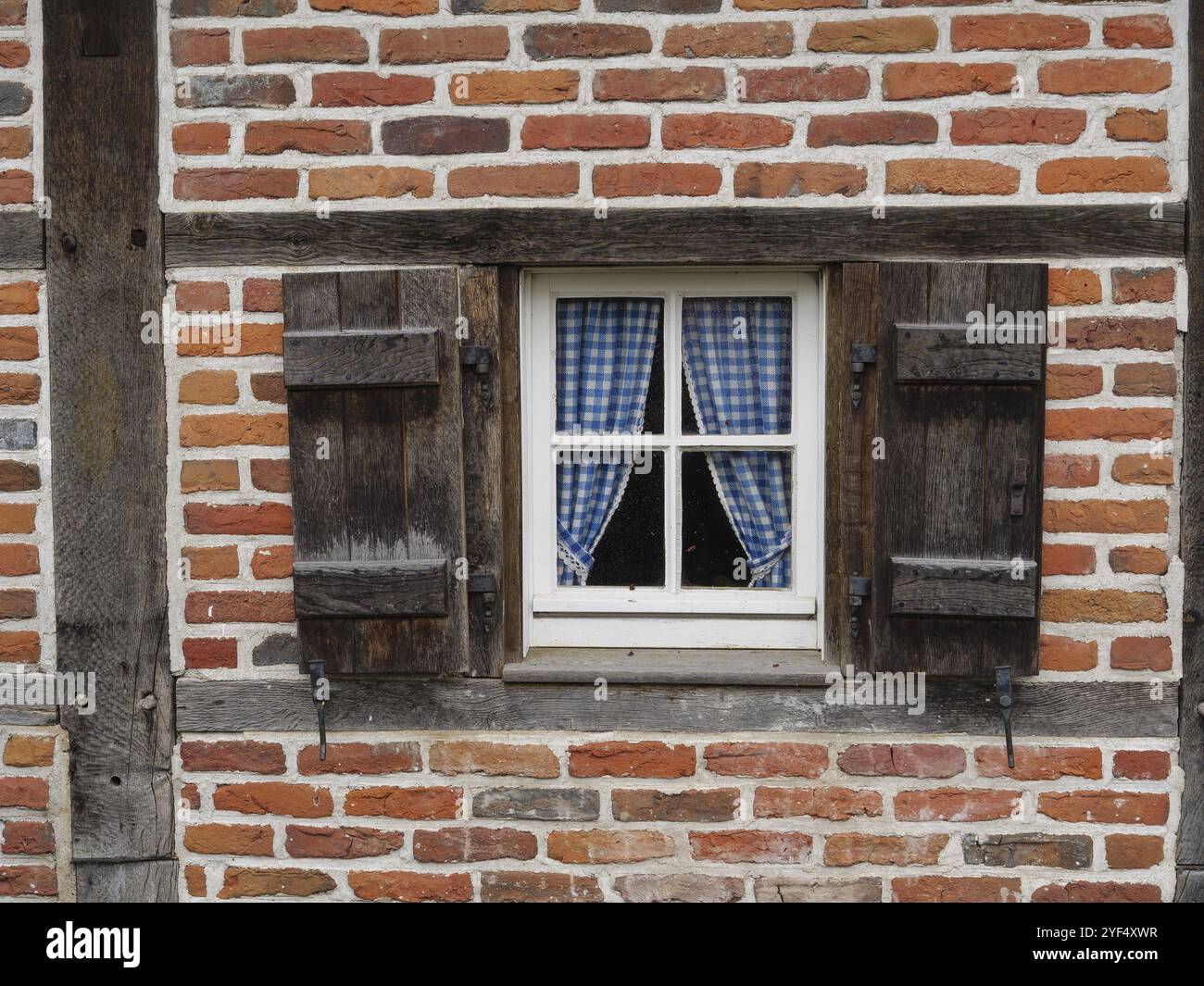 Kleines Fenster in einer Backsteinmauer, eingerahmt von Holzläden und Vorhängen, weseke, münsterland, deutschland Stockfoto Kleines Fenster in einer Backsteinmauer, eingerahmt von Holzläden und Vorhängen, weseke, münsterland, deutschland Stockfoto