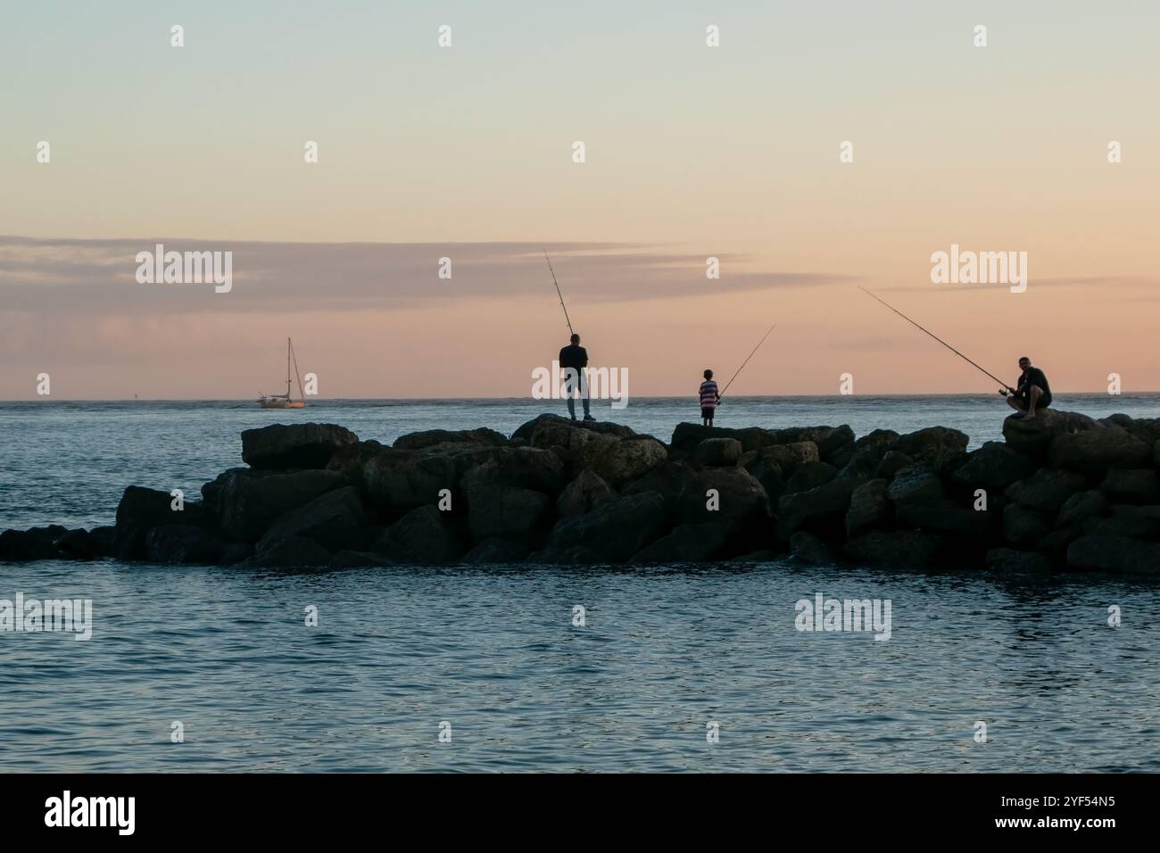 Fischer mit Angelrute am Pier bei Sonnenuntergang, Oeiras, Portugal Stockfoto