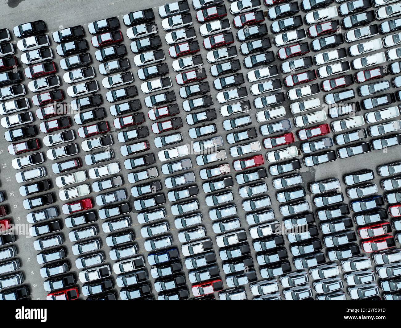 Luftaufnahme des Bestands neuer Autos auf einem großen Fabrikparkplatz. Automobilindustrie, Logistikbetrieb und Fahrzeuglagerung für Import und Export. Stockfoto