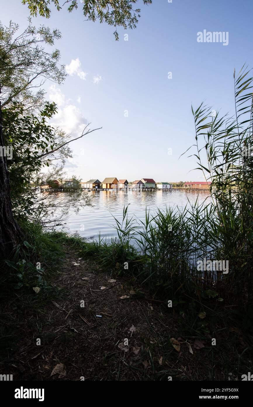 Holzhäuser im Wasser bei Sonnenuntergang. Lange Holzwege des schwimmenden Dorfes Bokodi am Balaton, Ungarn Stockfoto