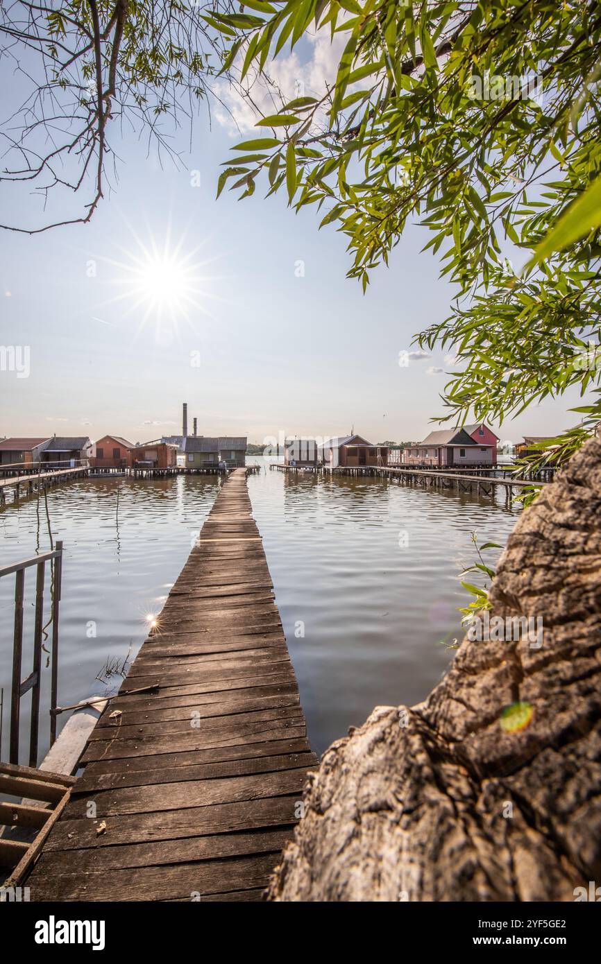 Holzhäuser im Wasser bei Sonnenuntergang. Lange Holzwege des schwimmenden Dorfes Bokodi am Balaton, Ungarn Stockfoto