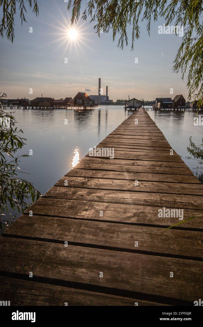 Holzhäuser im Wasser bei Sonnenuntergang. Lange Holzwege des schwimmenden Dorfes Bokodi am Balaton, Ungarn Stockfoto