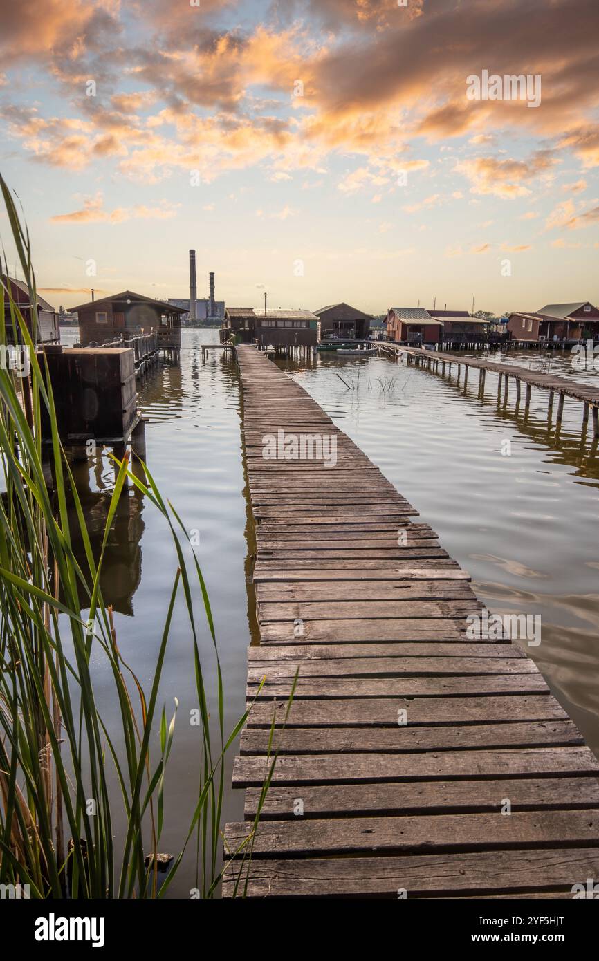 Holzhäuser im Wasser bei Sonnenuntergang. Lange Holzwege des schwimmenden Dorfes Bokodi am Balaton, Ungarn Stockfoto
