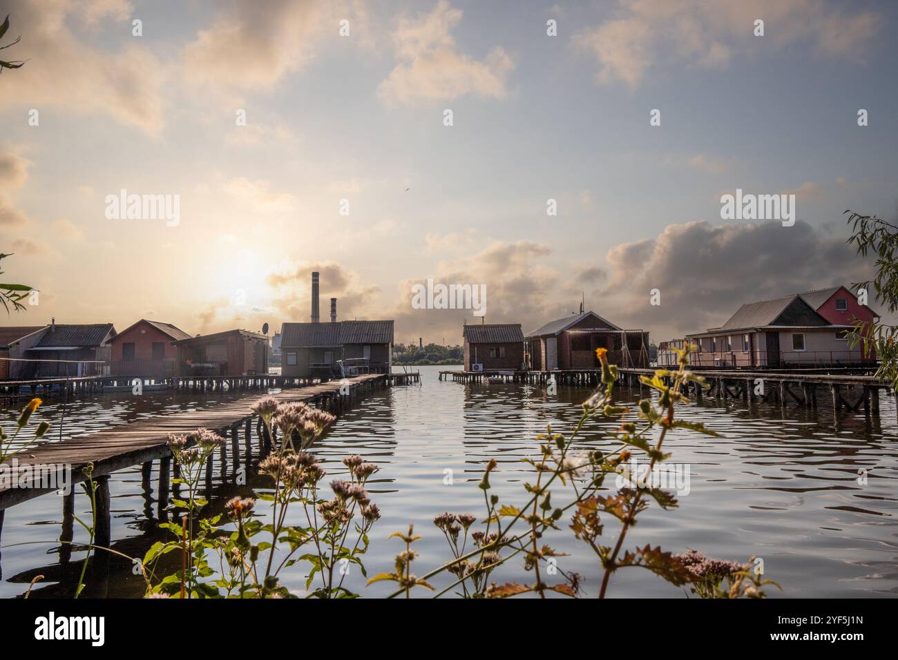 Holzhäuser im Wasser bei Sonnenuntergang. Lange Holzwege des schwimmenden Dorfes Bokodi am Balaton, Ungarn Stockfoto