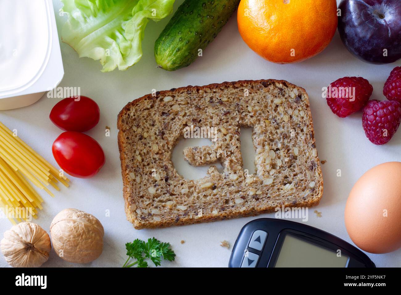 Vollkornbrotscheibe mit dem Symbol GI Cut out, Glucometer und Produkte mit niedrigem glykämischen Index, kreatives Konzept Stockfoto