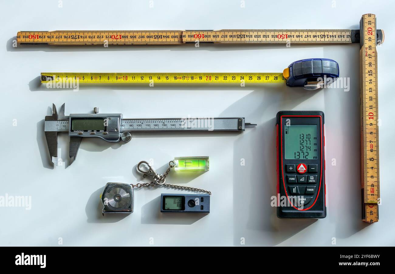 Auswahl an Messwerkzeugen (Laser-Entfernungsmesser, Bandmaß, Falzlineal, Ebene, Mini-Entfernungsmesser, Bremssattel) Stockfoto