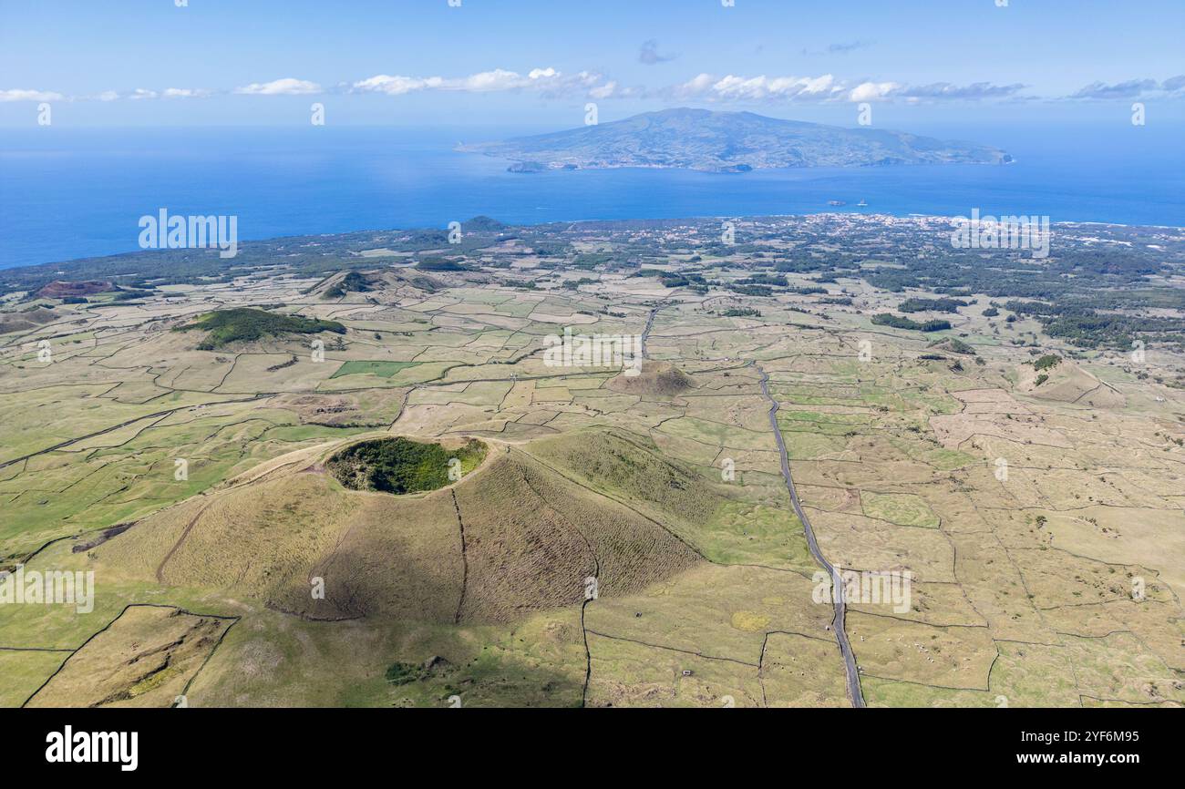 Luftaufnahme des westlichsten Teils der Insel Pico mit dem Vulkankrater Cabeco Gordo im Vordergrund und der Insel Faial in der Ferne - Azoren Stockfoto