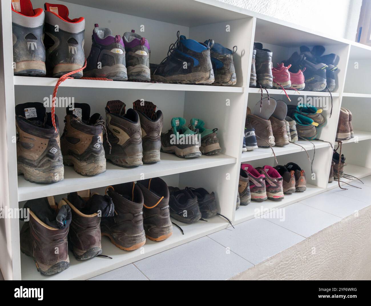 Mehrere Paar gut getragene Wanderschuhe sind in Regalen angeordnet, was auf die jüngsten Entdeckungen und Abenteuer im Freien hinweist. Stockfoto
