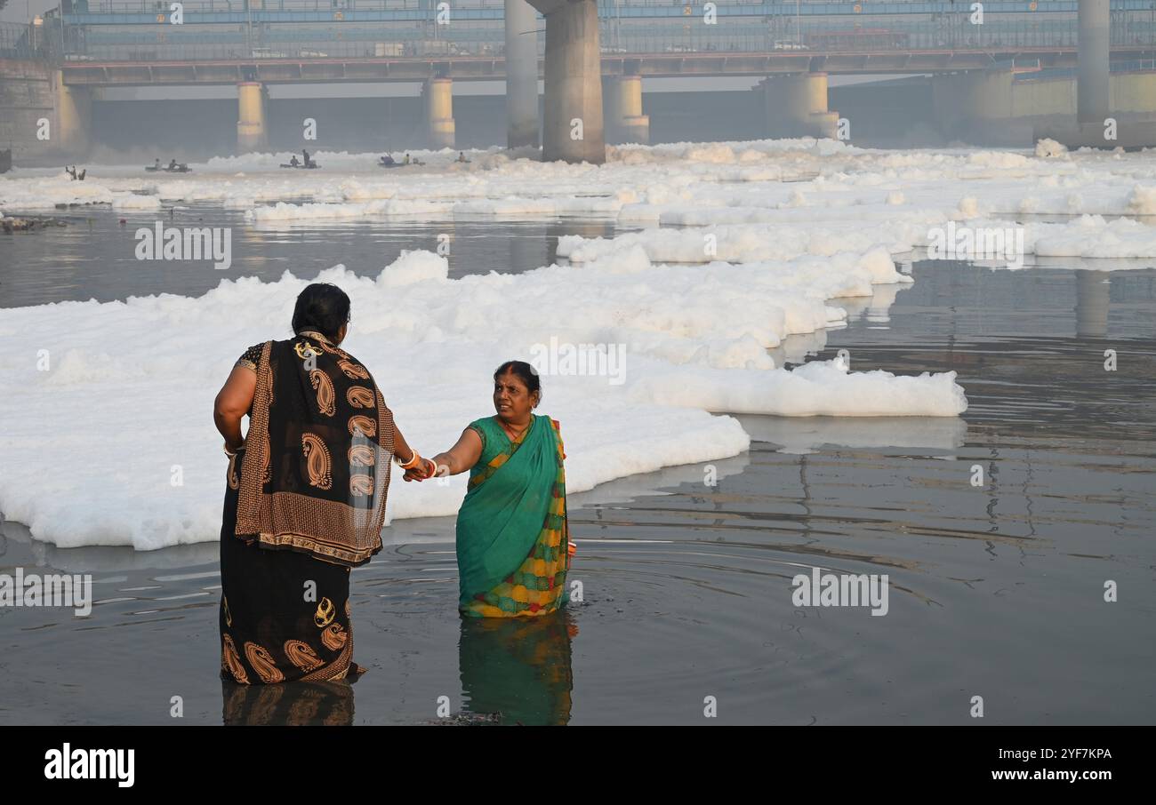 NEW DELHI, INDIEN – 3. NOVEMBER: Devotees führen vor Chhath Puja Rituale durch, während giftiger Schaum am 3. November 2024 in Neu-Delhi, Indien, auf der Oberfläche des Yamuna River bei Kalindi Kunj schwimmt. Der Yamuna River ist vor Chhath Puja, der vom 6. Bis 8. November gefeiert wird, mit giftigem Schaum überflutet, was Bedenken über die zunehmende Verschmutzung in Delhi-NCR weckt. Der Schaum, der auf eine starke Verschmutzung hinweist, hat die Behörden dazu veranlasst, chemische Entschäumer einzusetzen, um das Problem zu mindern. (Foto: Ajay Aggarwal/Hindustan Times/SIPA USA) Credit: SIPA USA/Alamy Live News Stockfoto