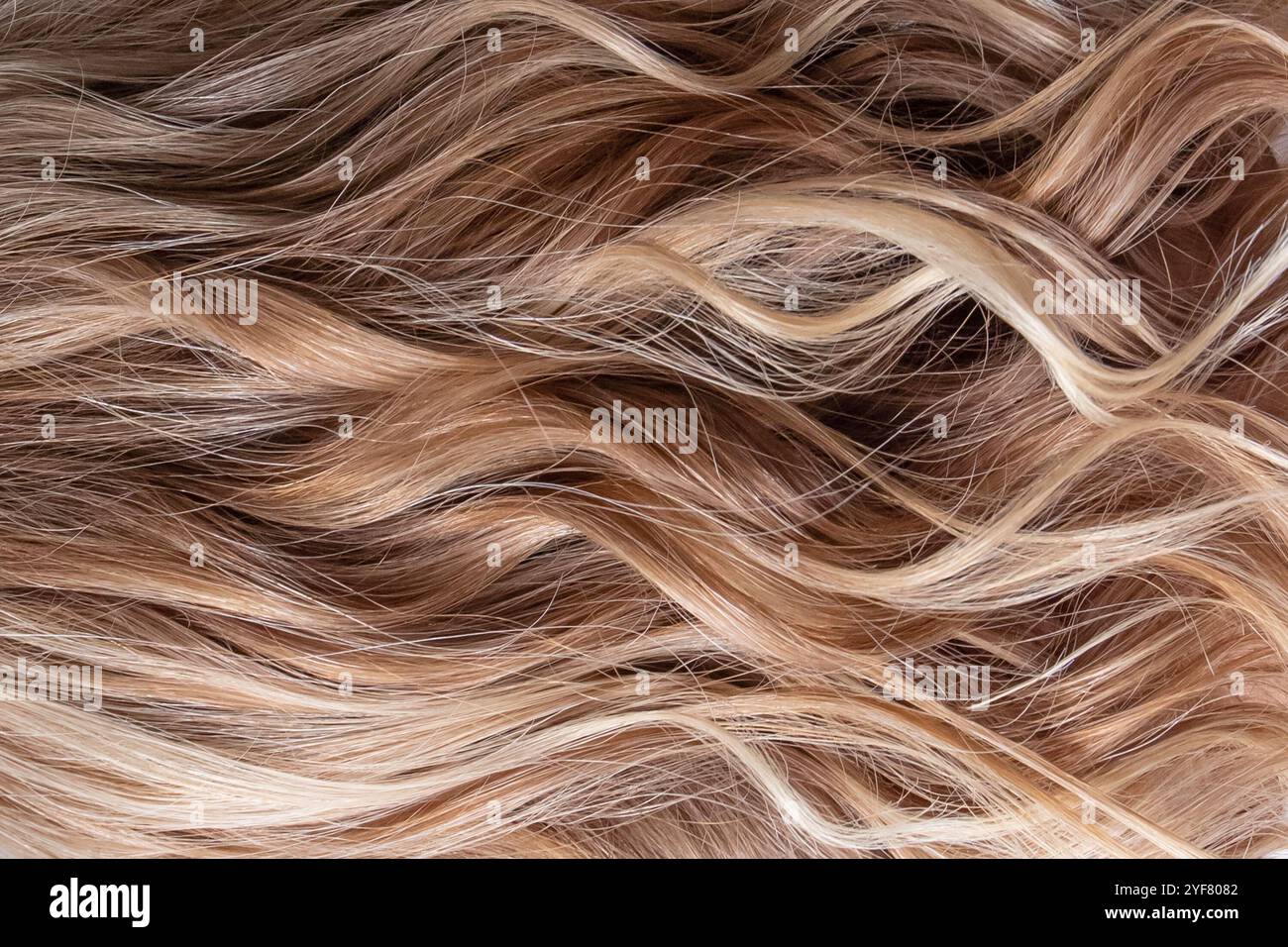 Blondes Haarstrukturmuster. Wellenförmiges Design. Helle Lichter. Haarfarbe. Stockfoto