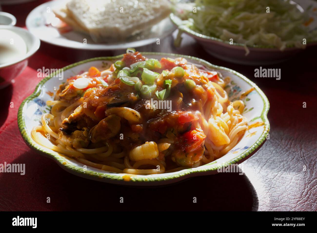 Pasta mit Meeresfrüchten eine Garnitur mit gehackten Frühlingszwiebeln, Hintergrundbeleuchtung, Beilagen, Brotbutter, Meeresfrüchten, dekorierter Teller, Norfolk, UK Stockfoto