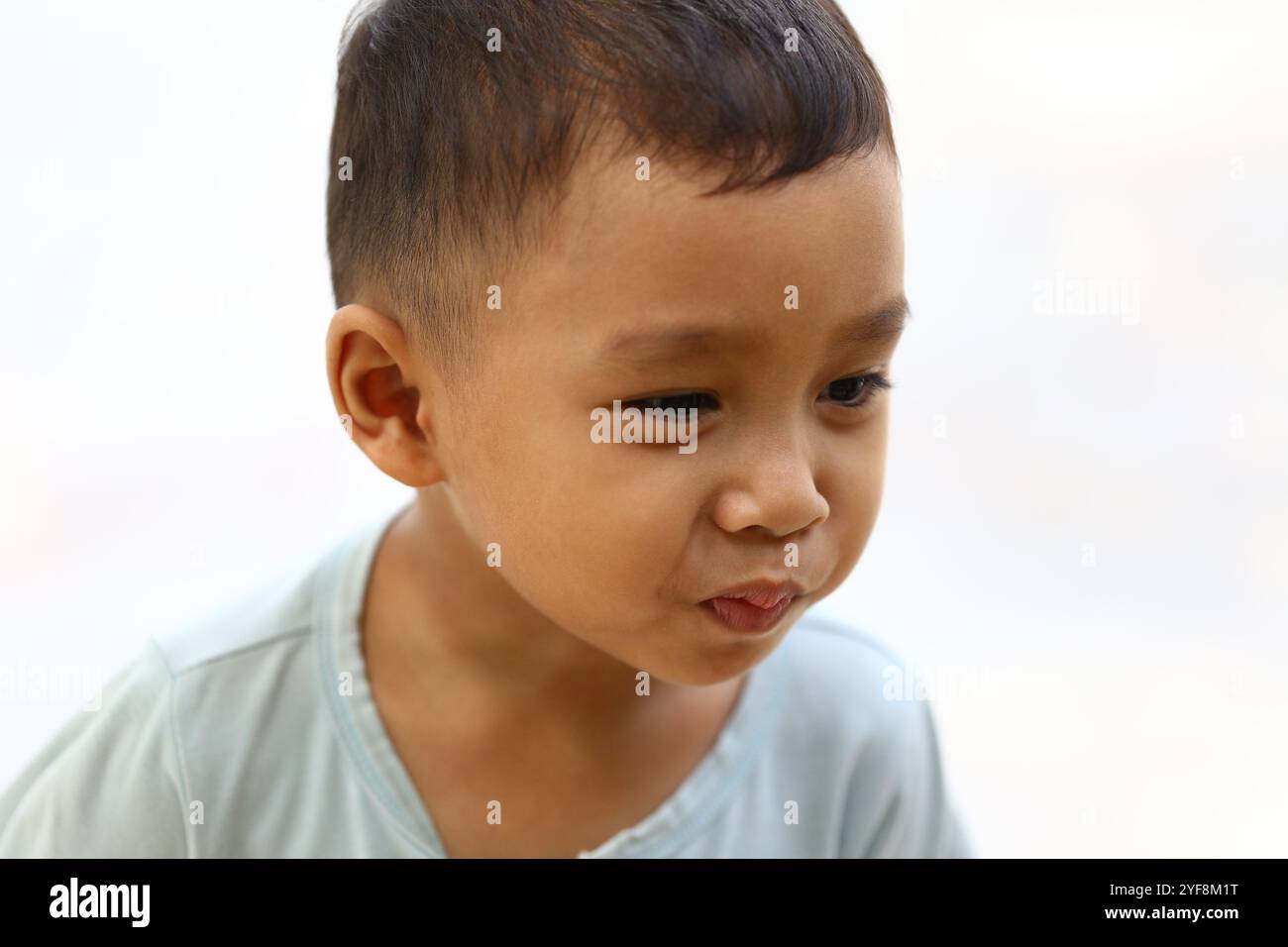 Ein kleiner Junge zeigt einen nachdenklichen Ausdruck, der in sanfter Beleuchtung festgehalten wird. Sein ruhiges Auftreten weckt Emotionen der Neugier und Unschuld, perfekt für Familien Stockfoto