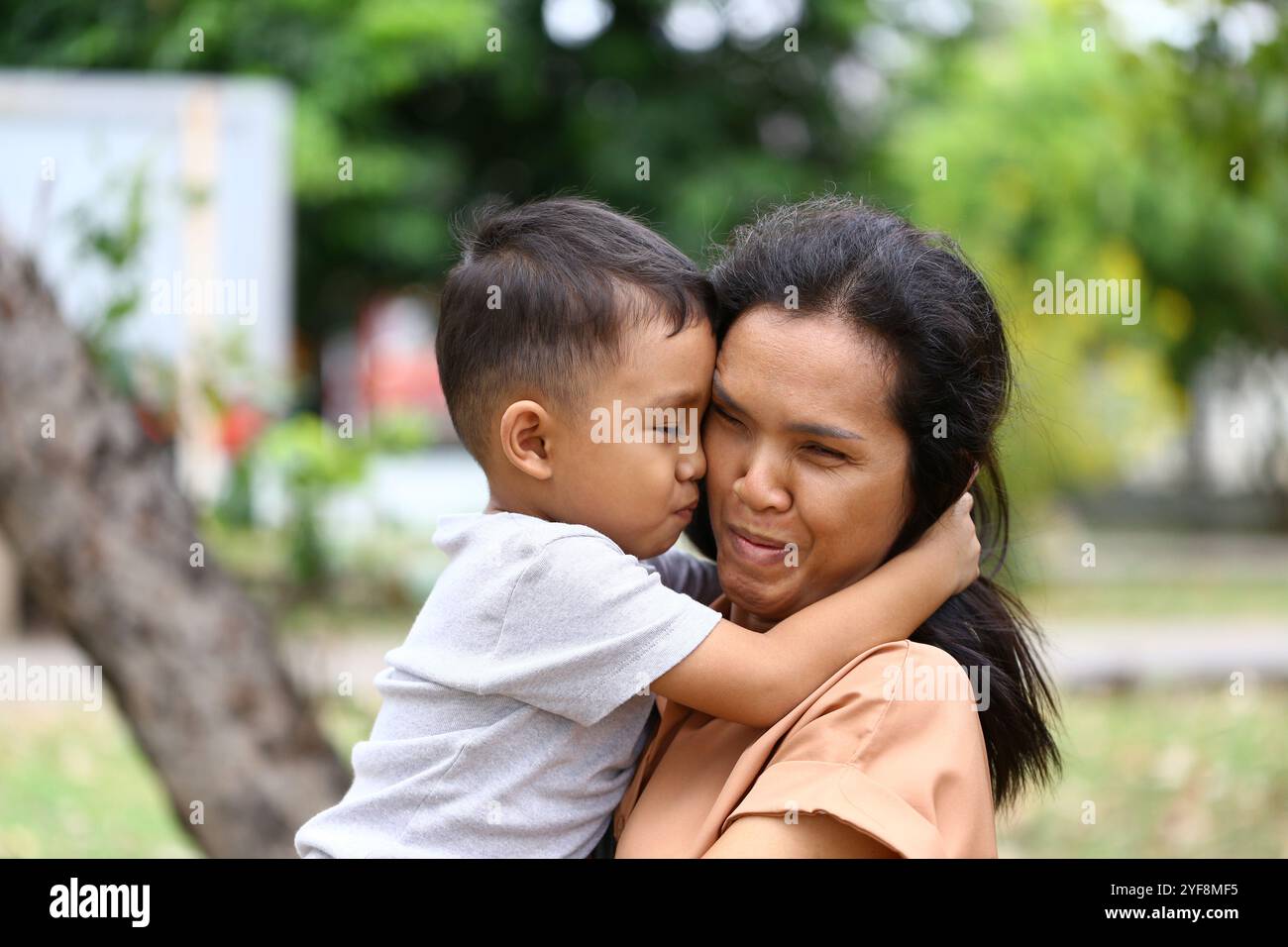 Ein herzerwärmender Moment zwischen einer Mutter und ihrem Kind, der Liebe und Zuneigung in einer ruhigen Umgebung im Freien zeigt und die Schönheit ihrer Bindung festhält. Stockfoto