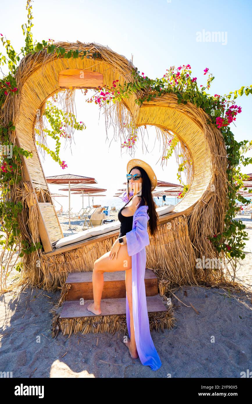 Elegante Sommer-Vibes mit modischer Frau, die in der herzförmigen Beach Cabana posiert Stockfoto