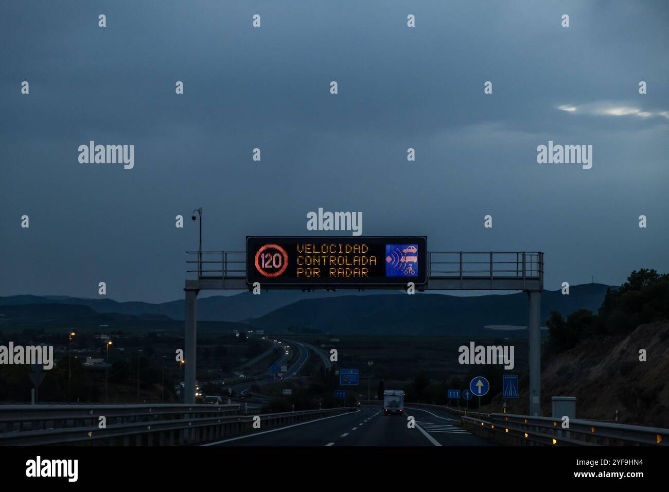 Nachtfotografie des Verkehrs auf einer Autobahn. Im Vordergrund befindet sich ein Lichtschild über der Straße, das anzeigt, dass die Geschwindigkeit von gesteuert wird Stockfoto