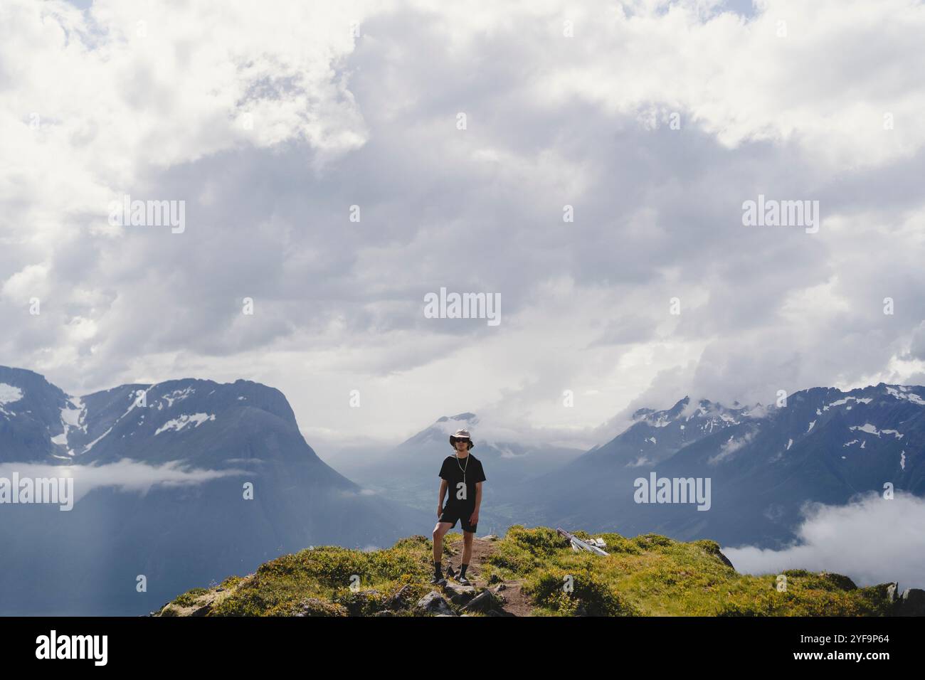 Die ganze Länge eines jungen Mannes, der auf dem Berg vor bewölktem Himmel steht Stockfoto