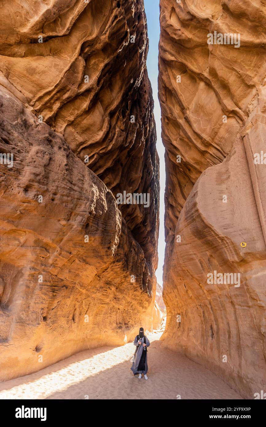 AL ULA, SAUDI-ARABIEN - 9. NOVEMBER 2021: Ortskundiger Reiseleiter in der engen Passage durch den Berg Jabal Ithlib, den Siq, bei Hegra (Mada'in Salih) in der Nähe Von A Stockfoto