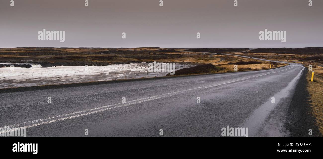 Leere Asphaltautobahn Hauptstraße mit eiskalt gefrorenem See in Island Stockfoto