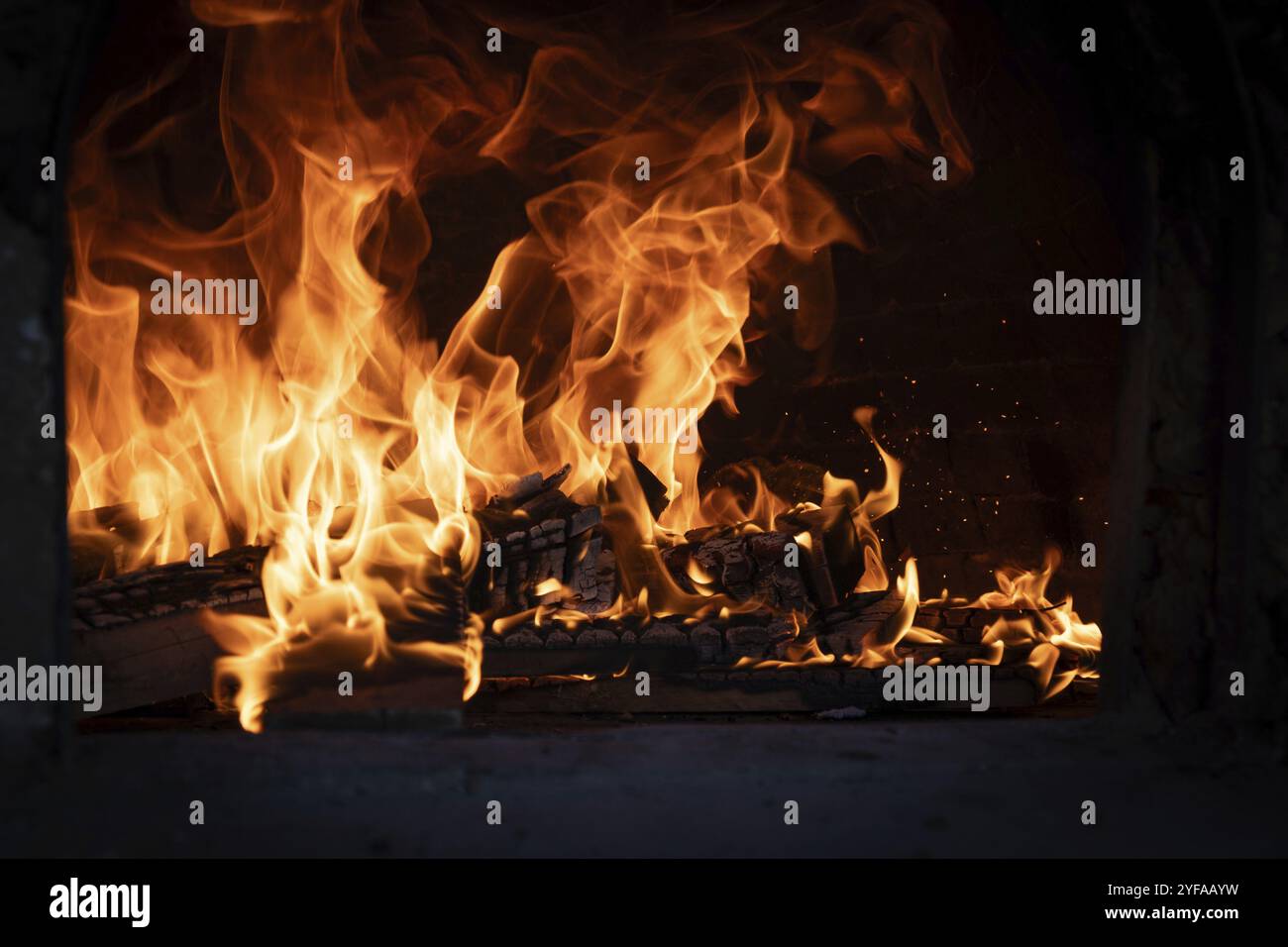 Feuer und verbrenne Kohle im Steinofen. Ofen aus Ziegeln und Ton. Lehmofen zum Kochen von Speisen und Pizza Stockfoto