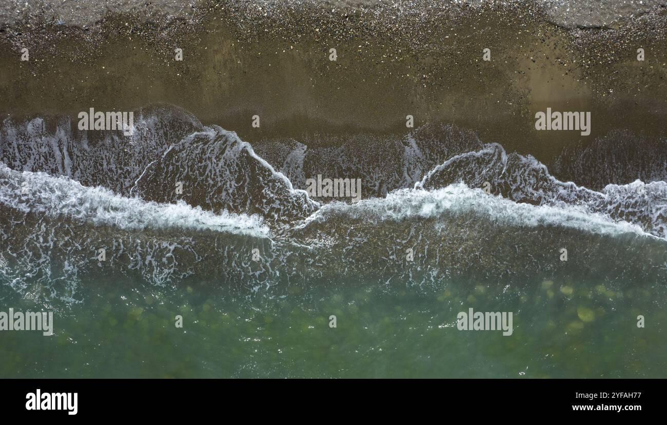 Luftaufnahme der Meereswellen, die an einem Sandstrand bremsen. Natur Hintergrund Stockfoto