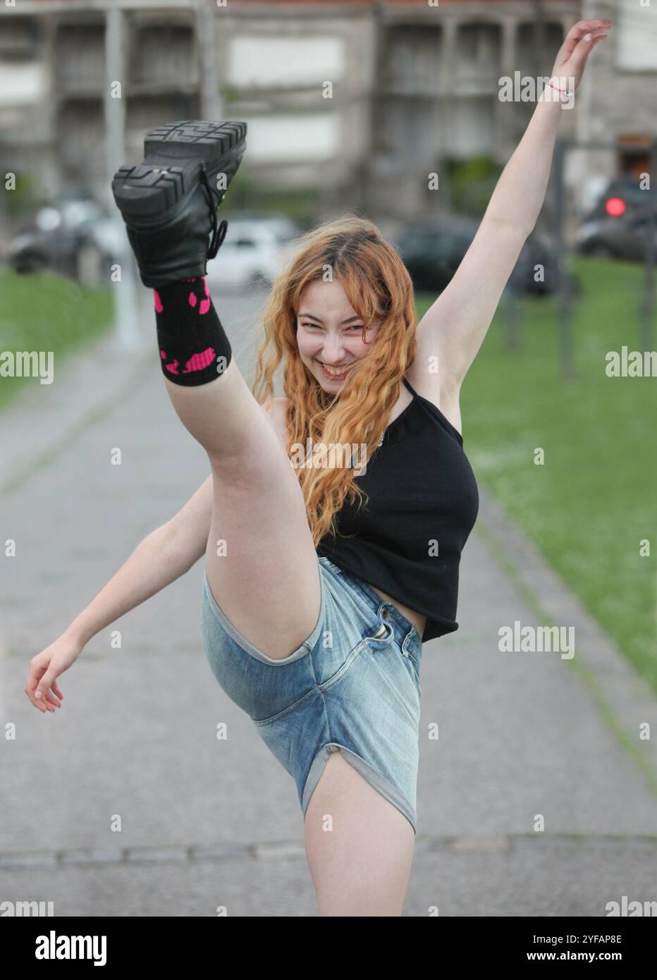 Süßes, fröhliches Teenager-Mädchen, das draußen ihr Bein tritt Stockfoto