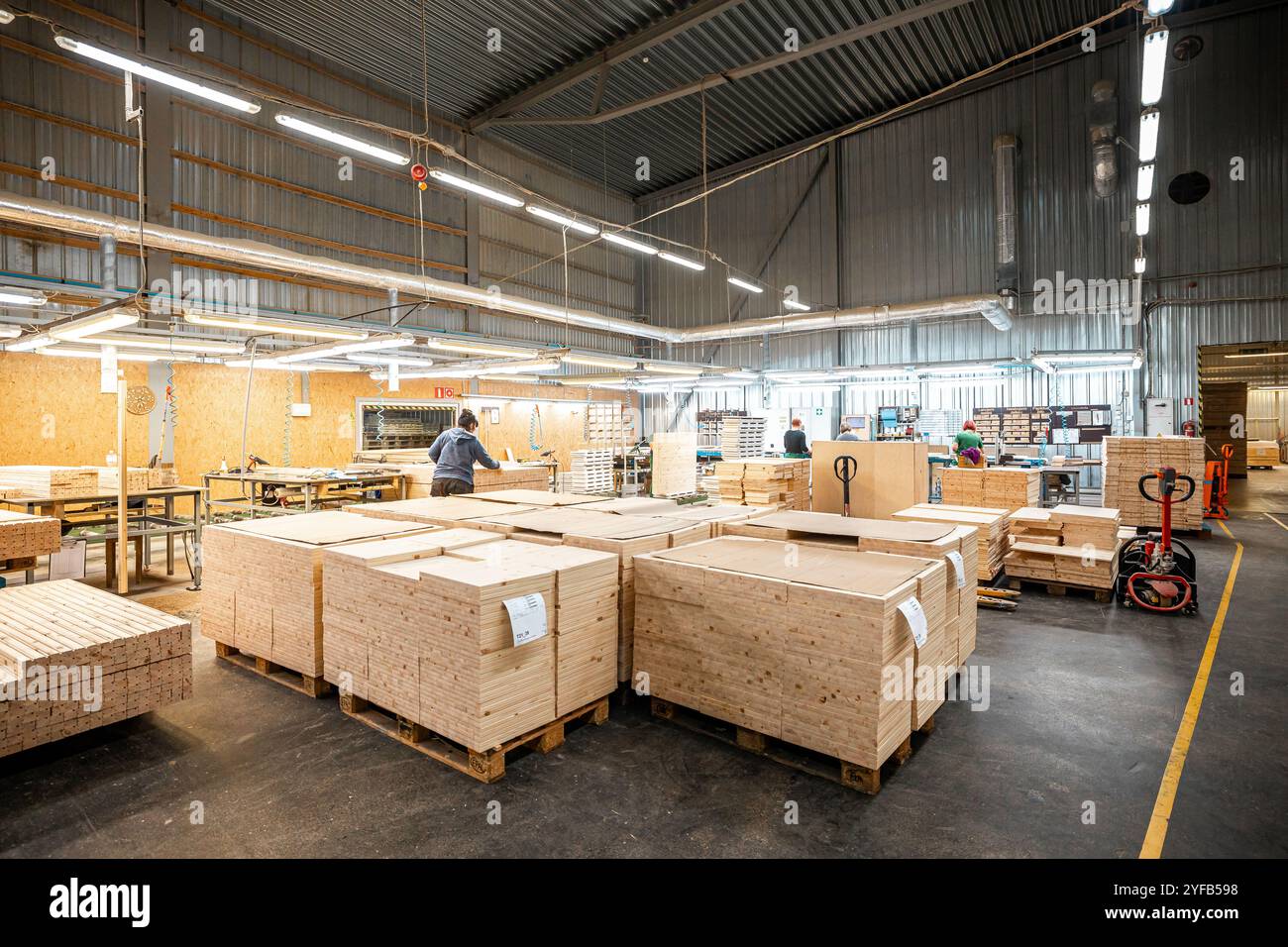 Eine große Holzbearbeitungsfabrik mit Stapeln frisch geschnittener Holzplatten, die für die Verarbeitung bereit sind und industrielle Effizienz und Präzision in einer guten Hand zeigen Stockfoto