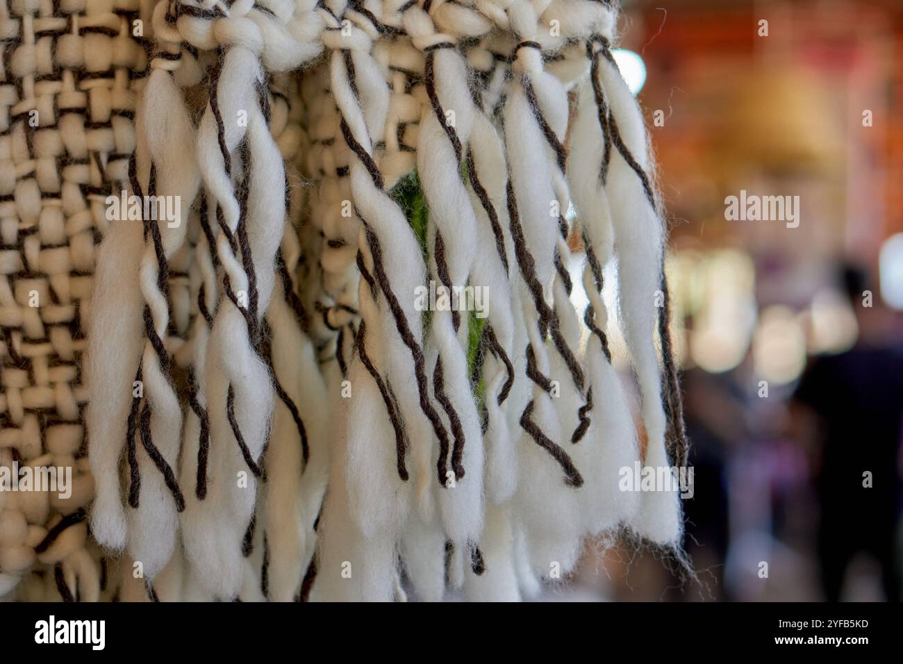 Nahaufnahme von handgefertigten Quasten aus Wandbehang, gestrickt mit schwarzem und weißem Garn Stockfoto