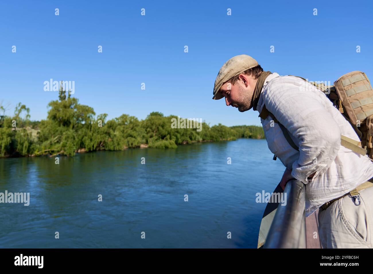 Junger Mann blickt von einem Aussichtspunkt über den Neuquen River. Verbindung mit der Natur in der Stadt im Frühling. Stockfoto