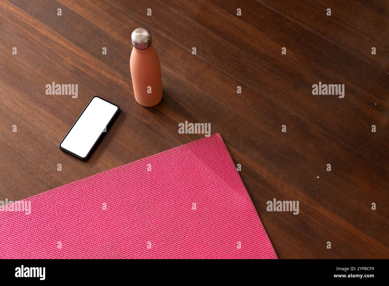 Yogamatte, Smartphone und Wasserflasche auf Holzboden für Heimtraining, Kopierraum Stockfoto
