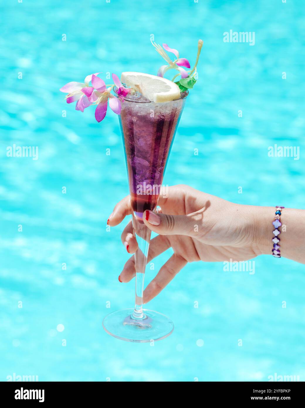 Ein lebhafter tropischer Cocktail am Pool, garniert mit Blumen und in einem erfrischenden rosafarbenen Farbton. Stockfoto