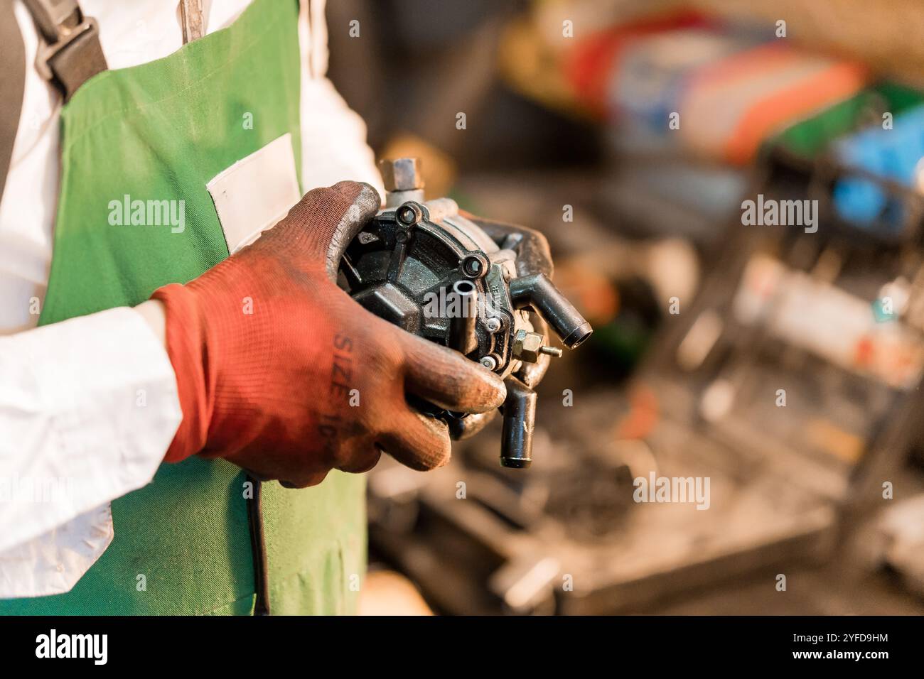 Ein Techniker, der eine mechanische Komponente in einer Werkstatteinstellung hält. Stockfoto