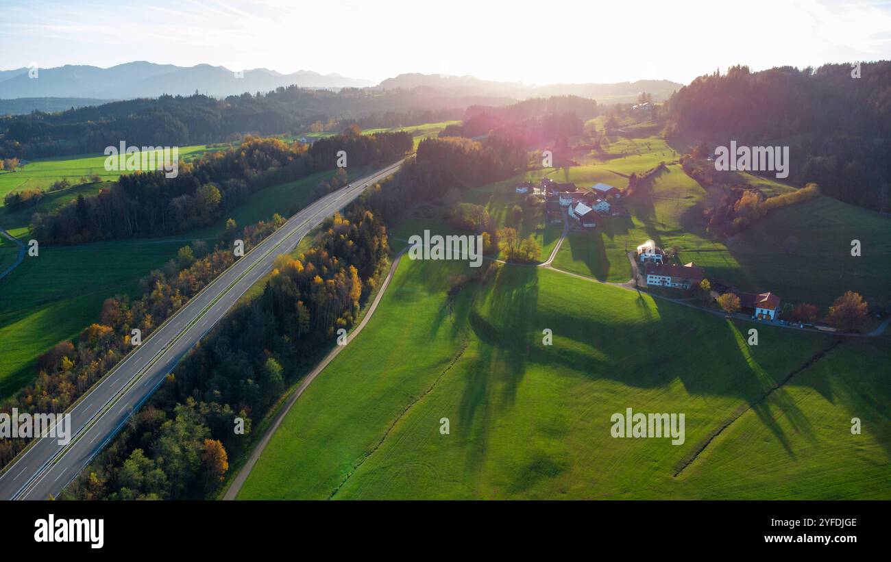 Allgäu, Bayern, Deutschland - 1. November 2024: Luftaufnahme der Allgäuer Landschaft bei Sonnenuntergang: Die B12 schlängelt sich durch sanfte Hügel, grüne Felder und Wälder, umgeben von idyllischen Bauernhöfen *** Luftaufnahme der Allgäuer Landschaft bei Sonnenuntergang: Die B12 schlängelt sich durch sanfte Hügel, grüne Felder und Wälder, umgeben von idyllischen Bauernhöfen Stockfoto