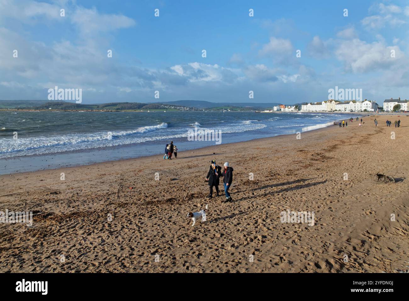 Menschen, die an einem windigen Wintertag am Exmouth Beach spazieren, Devon, Großbritannien, Dezember 2023. Stockfoto