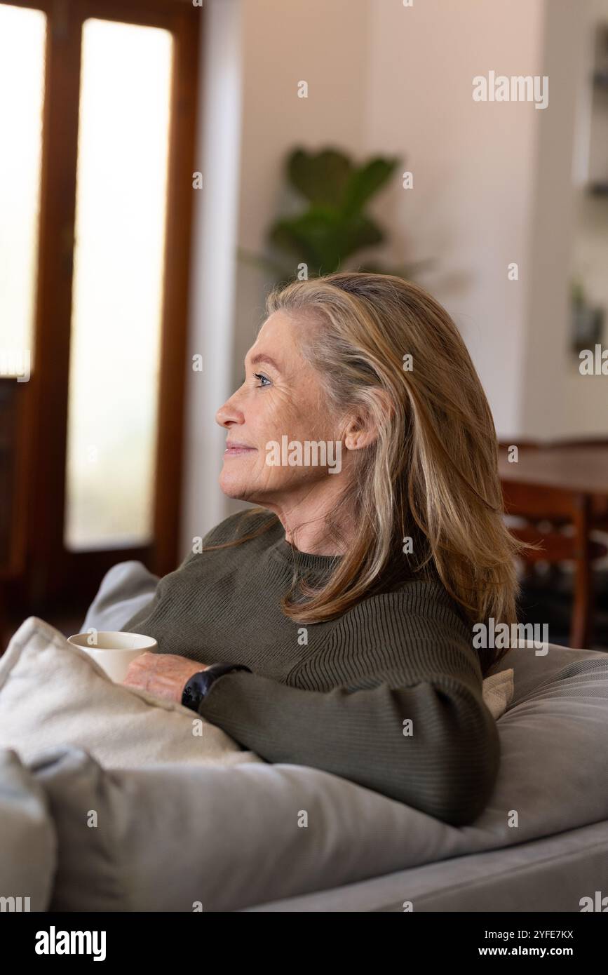 Entspannen Sie zu Hause, Seniorin genießt Kaffee und friedliche Momente auf dem Sofa Stockfoto