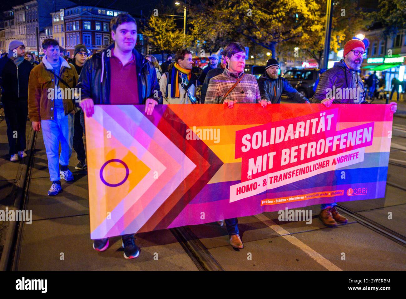 Rostock, Deutschland. November 2024. Demonstranten marschieren durch das Stadtzentrum, um gegen den mutmaßlichen Brandanschlag auf eine queere Bar zu protestieren. Nach Angaben der Polizei nahmen rund 1.500 Menschen an der Veranstaltung Teil. Quelle: Jens Büttner/dpa/Alamy Live News Stockfoto