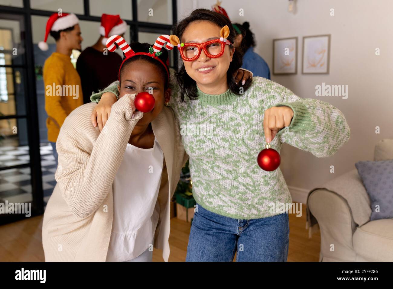 Festliche Accessoires tragen, multirassische Freunde feiern Weihnachten zu Hause und lächeln fröhlich Stockfoto