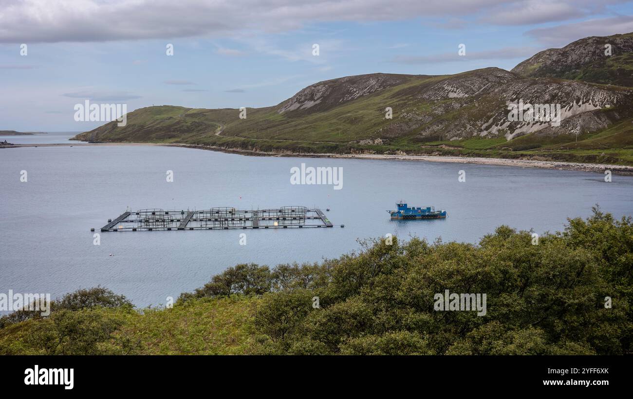 Lachsfarm in den runden Becken und ein blaues Fischerboot an der Nordwestküste des schönen Schottlands Stockfoto