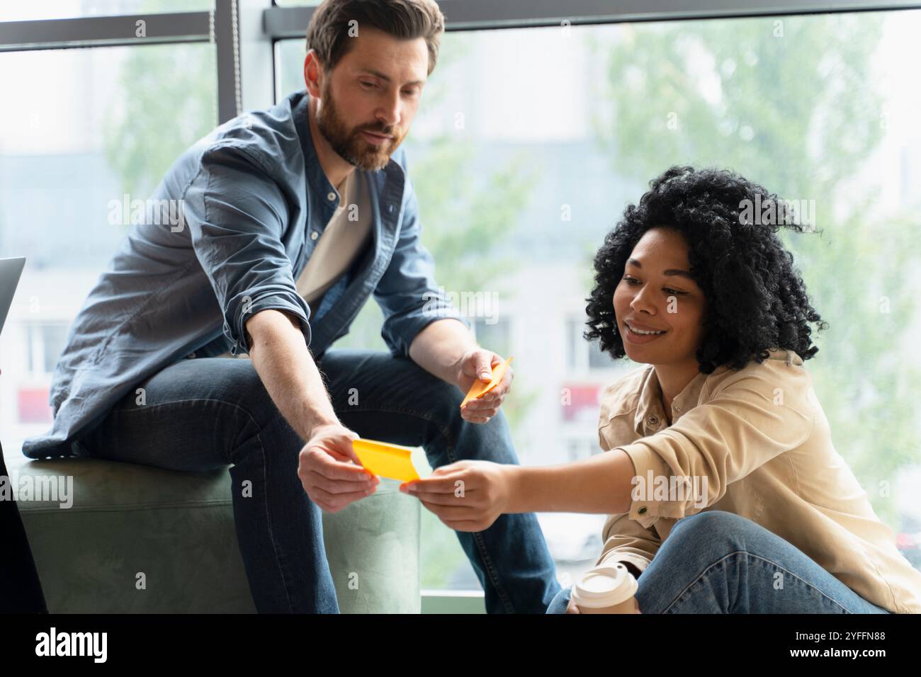 Zwei Geschäftsleute führen ein produktives Meeting und tauschen Ideen und Strategien aus, die auf Klebenotizen geschrieben sind, während sie an einem Projekt arbeiten Stockfoto
