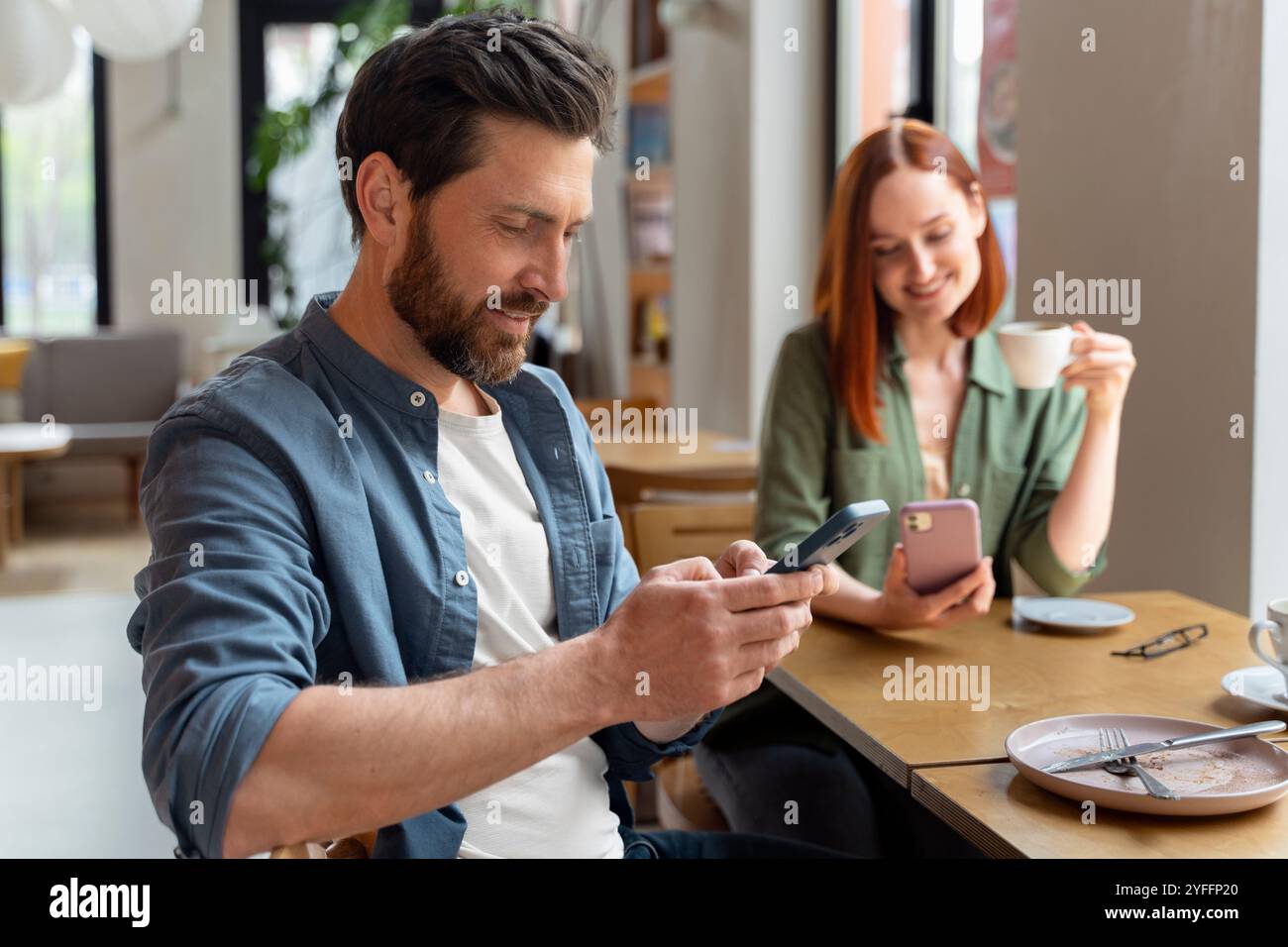 Paare verwenden Smartphones, während sie einen Kaffee in einem Café trinken, und genießen einen Moment der Entspannung und Verbindung Stockfoto