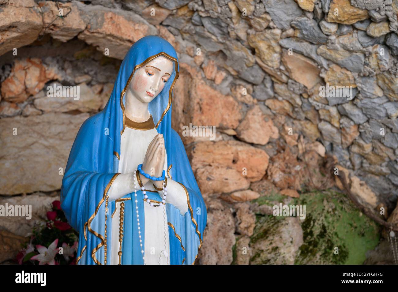 Unsere Lieben Frau von Lourdes – eine Statue in einer Grotte in der Nähe der Kirche des Heiligen Herzens Jesu in Studenci, Bosnien und Herzegowina. Stockfoto