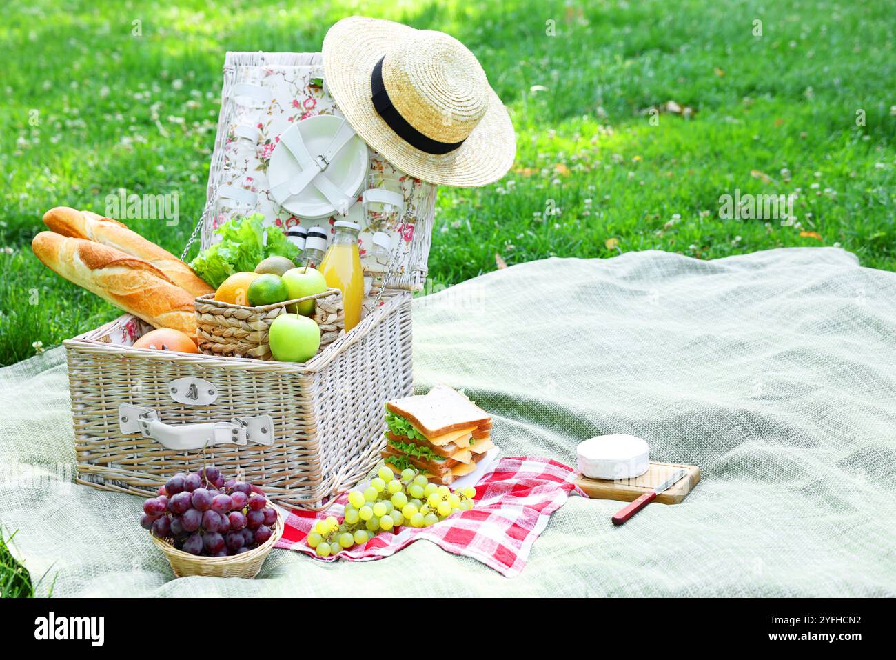 Picknick-Korb mit köstlichen Speisen und Getränken auf Decke im Freien Stockfoto